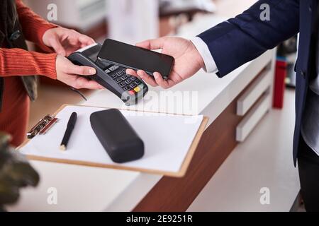 Purchaser paying with his smartphone in an optical shop Stock Photo