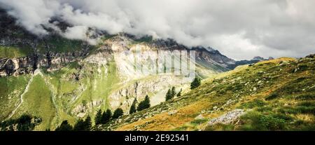 Panoramic view of rocky alpine mountains covered with clouds Stock Photo