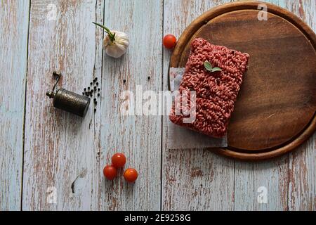 Minced Meat, Fresh raw beef whit black pepper, mint, basil and garlic served on plate on rustic wooden background Stock Photo