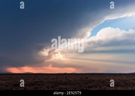 Crepuscular rays shining through dark storm clouds at sunset in the desert near Dell City, Texas Stock Photo