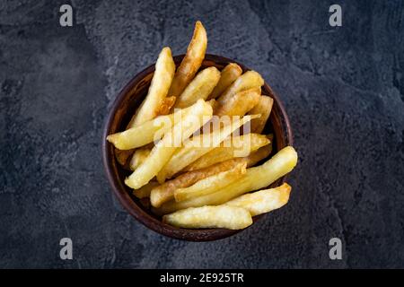 Bowl filled with crispy french fries on table Stock Photo