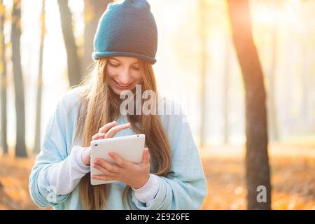 Lovely girl using tablet outdoors in autumn Stock Photo
