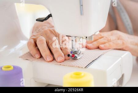 Close up view of old woman hands sewing on machine Stock Photo