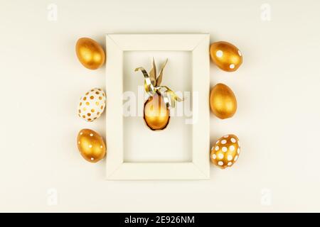 Easter festive decoration. Top view of easter eggs colored with golden paint and empty mock-up photo frame. Various dotted designs. White background Stock Photo