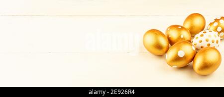 Easter festive decoration.Close up of easter eggs colored with golden paint on wooden background. Various dotted designs. Banner. Stock Photo