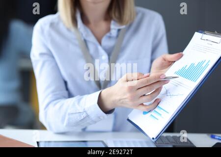 Business woman showing ballpoint pen on documents with graphs closeup Stock Photo