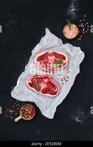 Fresh raw rack of lamb on wooden cutting board with herbs and seasoning Stock Photo
