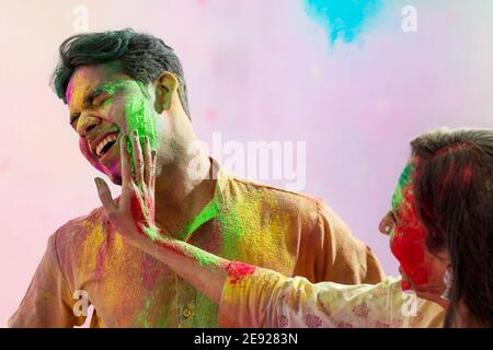 Wife putting gulal on her husband's face during Holi celebration Stock Photo