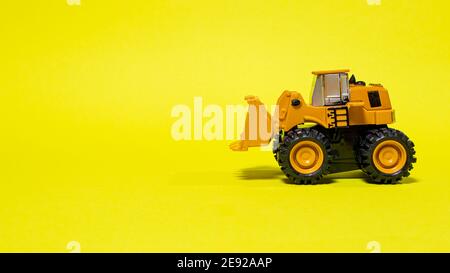 Toy typewriter tractor bulldozer on a yellow background. Toy for children. Stock Photo