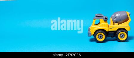 Orange concrete mixer toy typewriter on a blue background. A banner with a place for text for a toy store Stock Photo