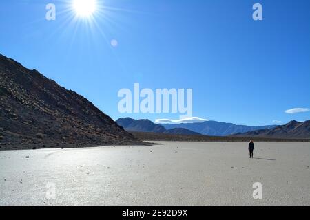 woman walking over Racetrack Playa on a cold December day in the Death Valley National Park, beautiful landscape with the moving rocks leaving tracks Stock Photo