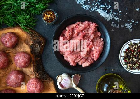 Homemade minced meat in a black bowl with ingredients. Fresh Raw mince for cooking meatballs. Top view. Stock Photo