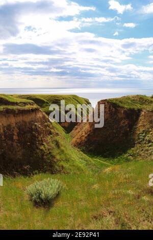Landscape view of cape from clay mountains and cliffs on sea. Seascape of coast from green meadows. Clay rock in front of sea. Sea view horizon Stock Photo