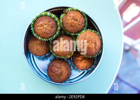 Muffins with wrappers placed in a metal box on a green table Stock Photo