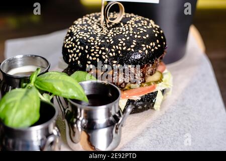 Burger and fries with sauce and tomatoes on a wood plate at a restaurant Stock Photo