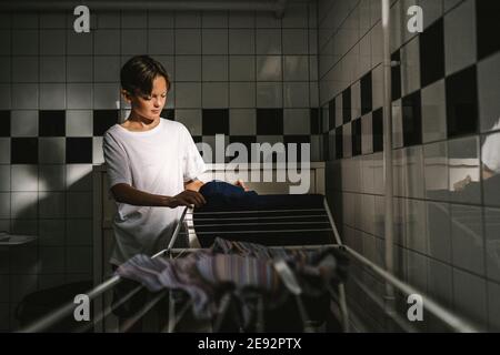 Boy doing laundry in utility room Stock Photo
