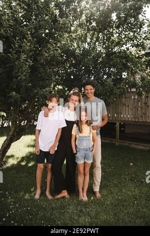 Happy family standing against tree in back yard Stock Photo