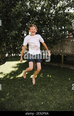 Cheerful boy jumping in back yard Stock Photo