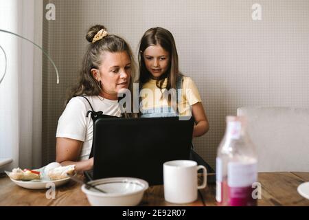 Mother and daughter using laptop at dining table Stock Photo