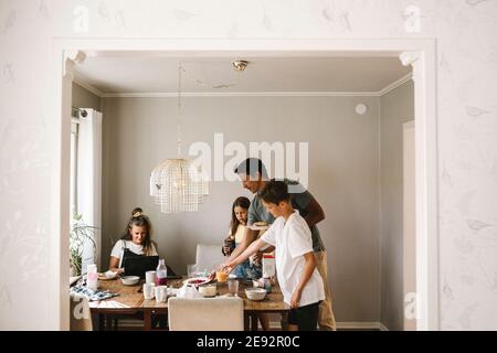 Family at dining table seen through doorway of house Stock Photo