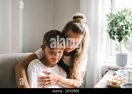 Smiling mother embracing son at home Stock Photo