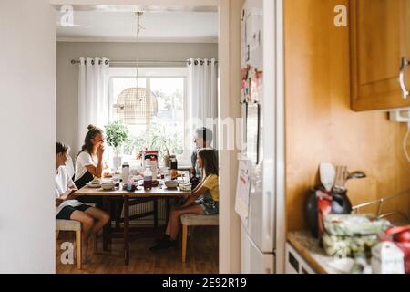 Happy family eating breakfast seen through doorway of kitchen at home Stock Photo