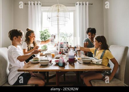 Parents having breakfast with children over table at home Stock Photo
