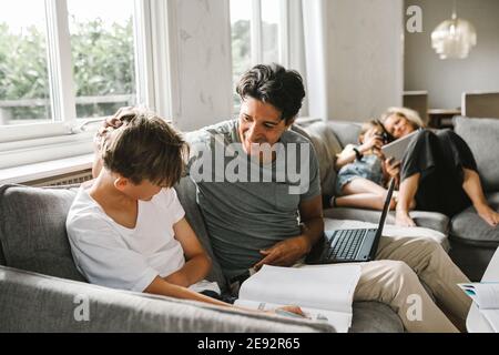 Happy father with son doing his homework at home Stock Photo