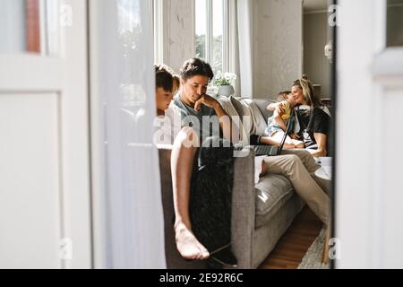 Parents sitting with children on sofa at home Stock Photo