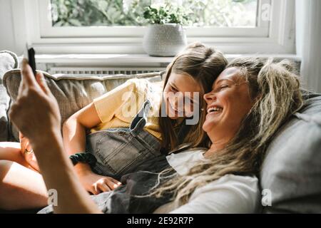 Smiling mother and daughter using digital tablet in living room Stock Photo