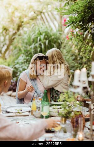 Girl whispering something in ear of female friend during party Stock Photo