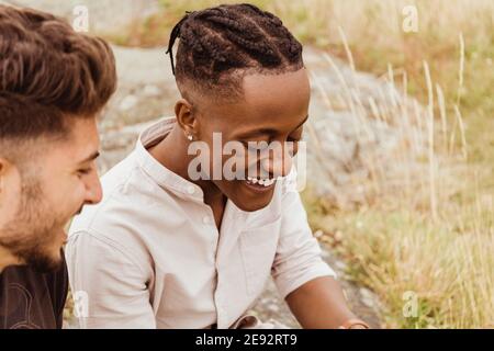Male friends laughing while sitting outdoors Stock Photo