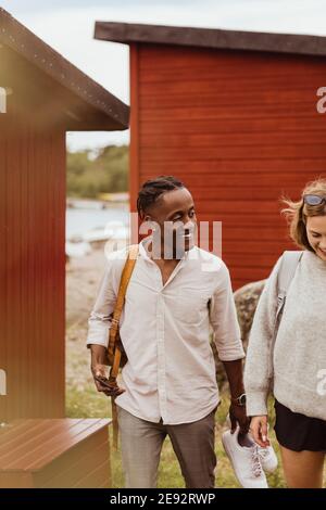 Smiling friends walking against cottage during vacation Stock Photo