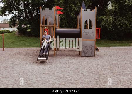 Father and baby son playing on slide at playground Stock Photo