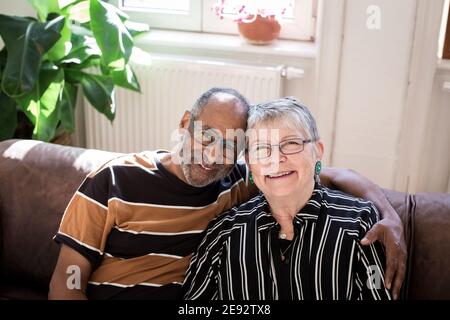 Smiling couple with arm around sitting on sofa at home Stock Photo