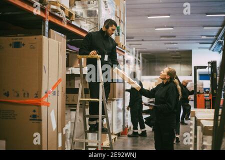 Male and female coworker holding package at logistics warehouse Stock Photo