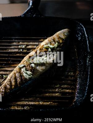 Grilling a whole fish on a grill pan at a restaurant Stock Photo