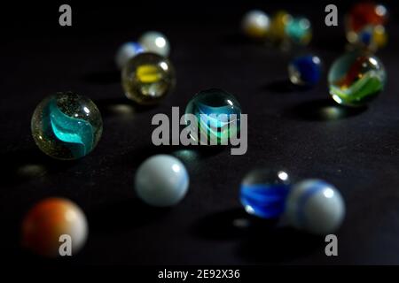 Colorful marbles with scattered swirl marbles on dark background Stock Photo