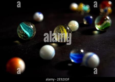 Colorful marbles with scattered swirl marbles on dark background Stock Photo