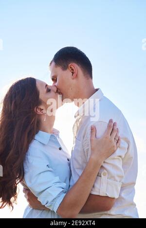 Stylish and modern couple kissing in a wheat field. A young woman hugs her boyfriend and kisses each other. The concept of passion and love. Stock Photo