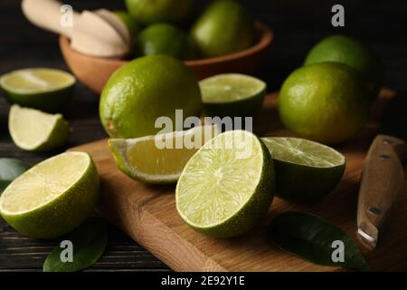 Bowl and board with lime on wooden background, close up Stock Photo