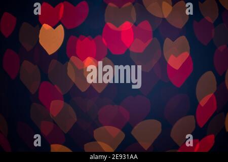 Multicolored blurred hearts, bokeh, lights on a black background, a symbol of love for Valentine's Day. Stock Photo