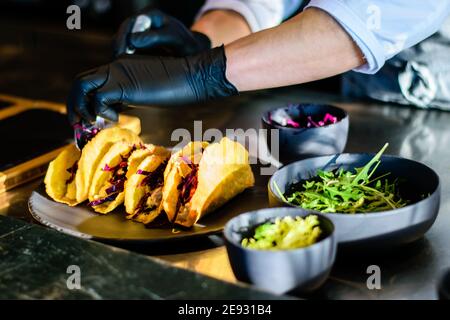 A chef plating tacos in a restaurant kitchen Stock Photo
