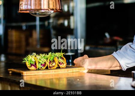 A chef plating tacos in a restaurant kitchen Stock Photo