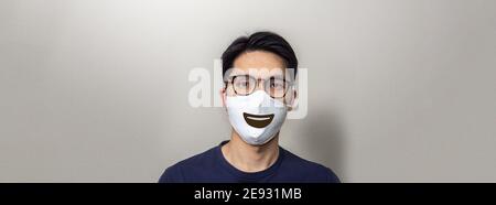 Smiley mouth printed on facial mask on Asian man Stock Photo