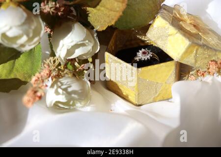 Engagement and Marriage silver diamond ring with a ruby in a Gift box with white background and bridal bouquet Stock Photo