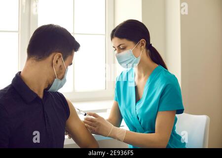 Professional nurse or doctor injects a patient with a flu or coronavirus vaccine in a modern clinic. Stock Photo