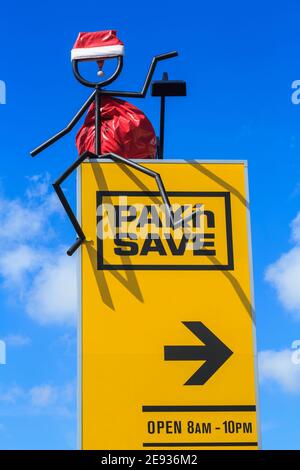 A Pak'nSave supermarket sign in New Zealand. Their 'stickman' mascot is decorated with a Christmas hat and Santa sack Stock Photo