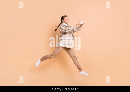 Full size profile photo of optimistic girl jump do photo wear white shirt trousers sneakers isolated on beige background Stock Photo