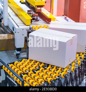 cardboard box of product packaging is moving on conveyor belt of automatic packing machine in the manufacturing factory Stock Photo